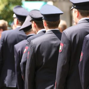 Una delegazione di pompieri tedeschi visti di spalle, in fila, mentre passa durante un evento pubblico