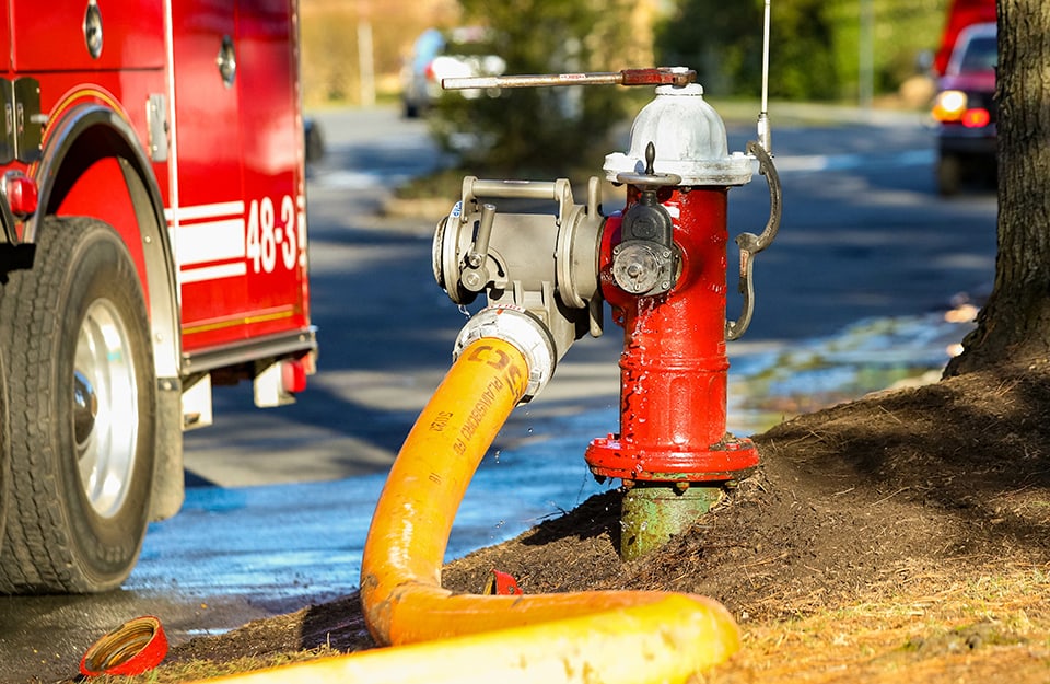 Una manichetta dei pompieri attaccata a un'idrante in un'anonima città degli Stati Uniti. Si vede parte di un camion dei pompieri