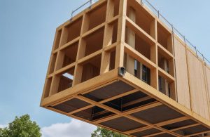 Un modulo in legno di un'architettura moderna viene spostato con una gru