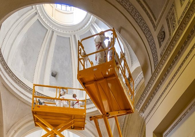 Dei restauratori stanno compiendo dei lavori di restauro in una chiesa su due ponteggi