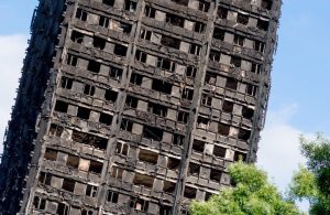 Vista ravvicinata della Grenfell Tower di Londra dopo l'incendio. L'orizzonte della fotografia è inclinato e la torre sembra sul punto di crollare