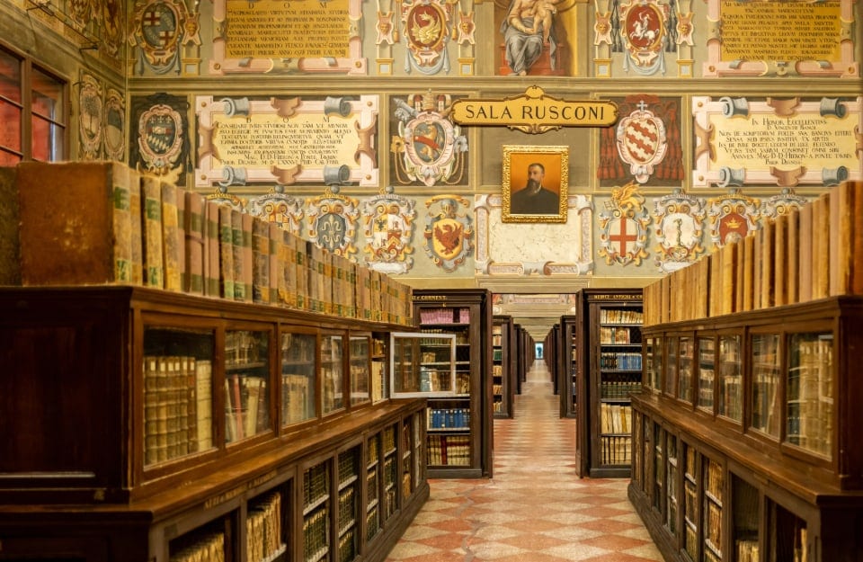 Una delle sale della storica Biblioteca dell'Archiginnasio di Bologna, con scaffali con libri antichi e pareti affrescate