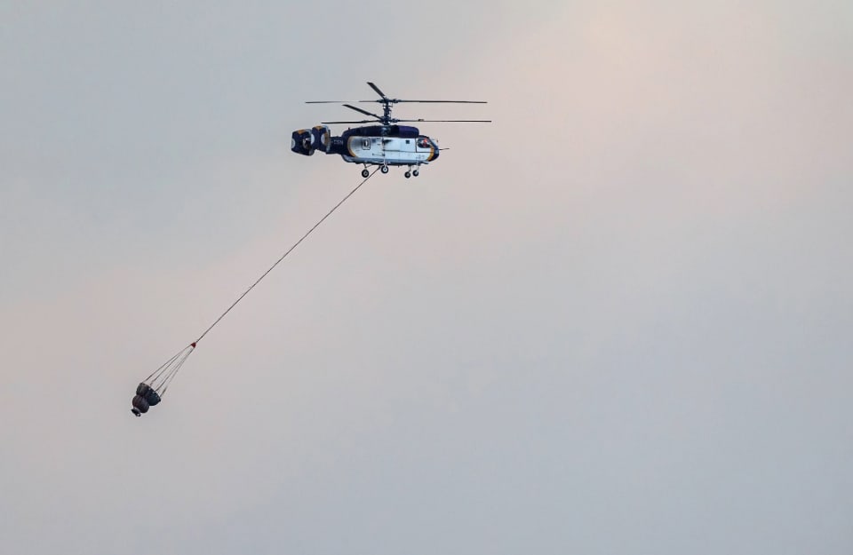 Un elicottero sta trasportando acqua per spegnere un incendio vicino all'aeroporto di Alessandropoli, in Grecia, nell'agosto del 2023