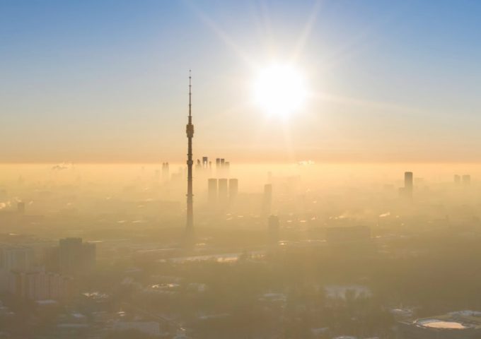 Vista dall'alto della torre di Ostankino, a Mosca, che spicca in un cielo terso sopra alla nebbia che avvolge il resto della città