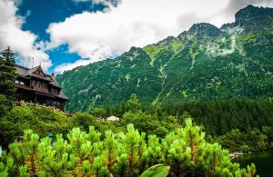 Vista dal basso e da lontano di un rifugio alpino in legno, in montagna, con molte persone all'esterno che guardano il panorama