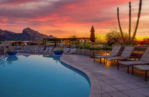 Piscina con sdraio in un villaggio turistico con vista panoramica sulle montagne, al tramonto