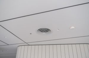 Dettaglio su una presa d'areazione nel soffitto di un ufficio, accanto a un'allarme antincendio