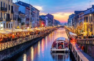 Il Naviglio Grande di Milano la sera al tramonto, con le due sponde piene di luci e affollate