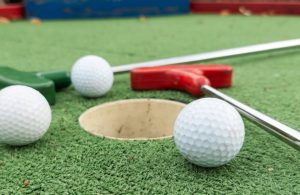 Dettaglio di una buca di un campo da mini-golf, con due palline e due mazze poggiate a terra