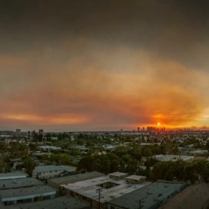 Il fumo dei devastanti incendi di Pacific Palisades e Hollywood Hills copre il cielo sopra il panorama dello skyline di Los Angeles al tramonto