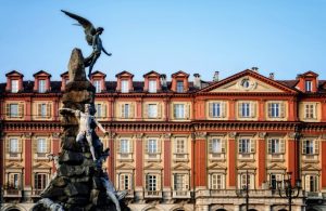 Vista di uno dei palazzi di Piazza Statuto, a Torino, con a sinistra parte del monumento al traforo del Fréjus