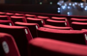 Alcune poltrone rosse e vuote di un cinema, con una porzione di schermo visibile