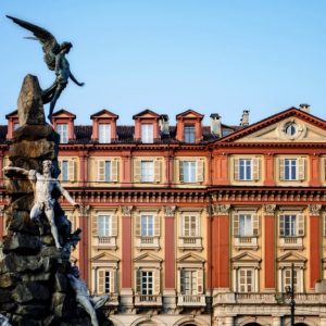 Vista di uno dei palazzi di Piazza Statuto, a Torino, con a sinistra parte del monumento al traforo del Fréjus